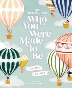 Book cover of ‘The World Needs Who You Were Made to Be’ by Joanna Gaines, featuring colourful, whimsical illustrations of a group of children joyfulling working together to build and fly hot air balloons, with each balloon uniquely designed to reflect their individuality, set against a bright, uplifting sky.