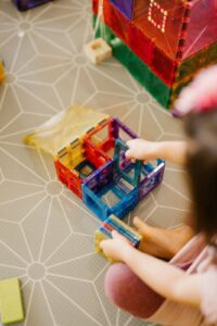 A toddler engaging with magnetic tiles to explore the properties of magnetism, experimenting with how tiles attract and repel each other, promoting hands-on learning in STEM concepts.