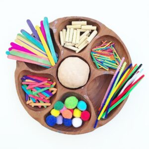 Tray set up with an assortment of loose parts for a playdough session, including pipe cleaners, pom poms, popsicle sticks, and other colorful items. The materials are arranged neatly, inviting creative exploration and imaginative play with playdough.