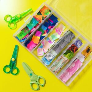 Scissors and various sizes of paper laid out for a toddler activity. The scissors are child-safe, and the papers come in different colors and dimensions, ready for cutting and crafting projects.